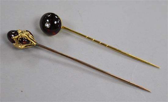 Two late Victorian yellow metal and garnet set stick pins including one with inset diamond.